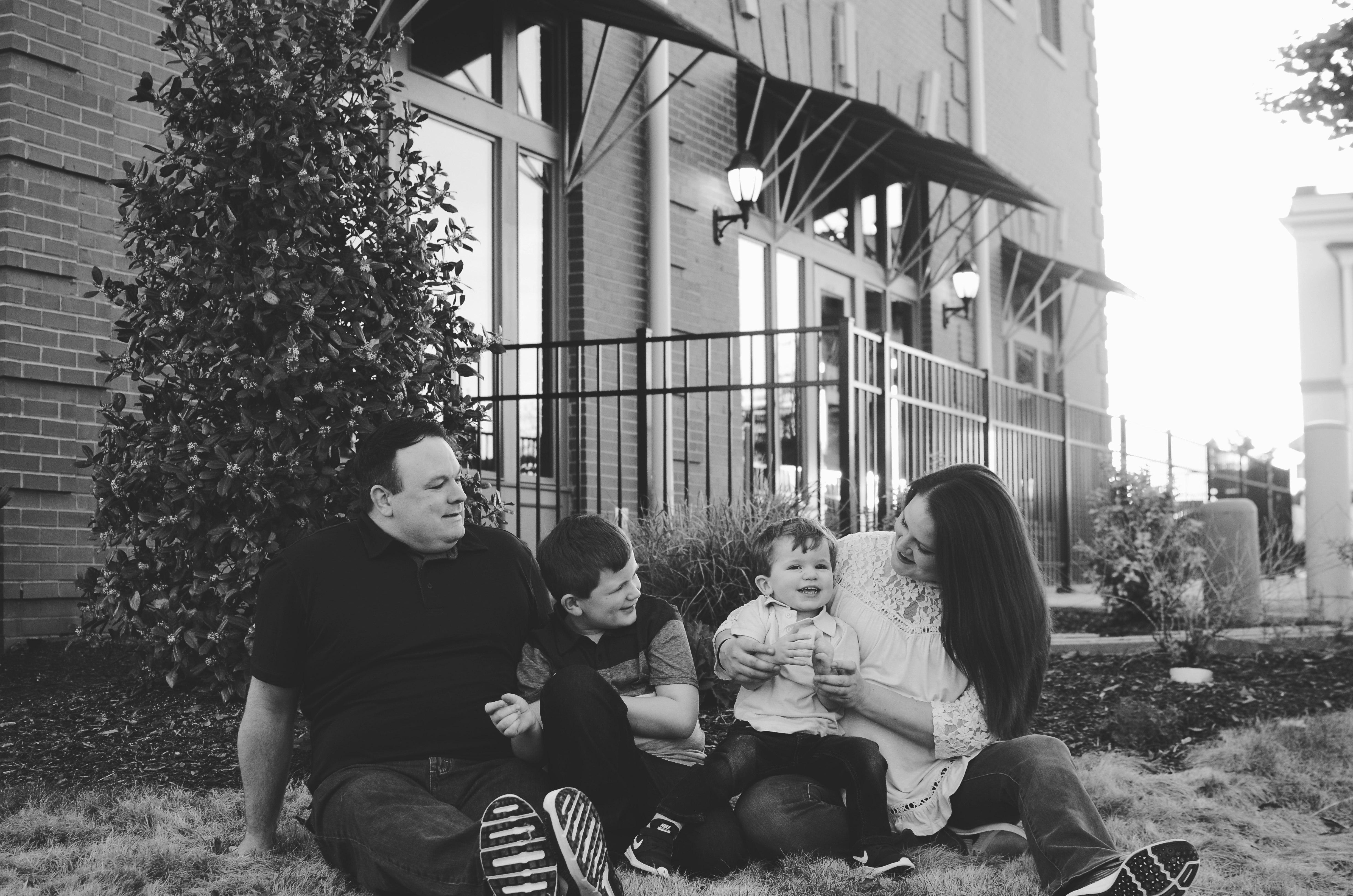 grayscale photography of family sitting beside tree